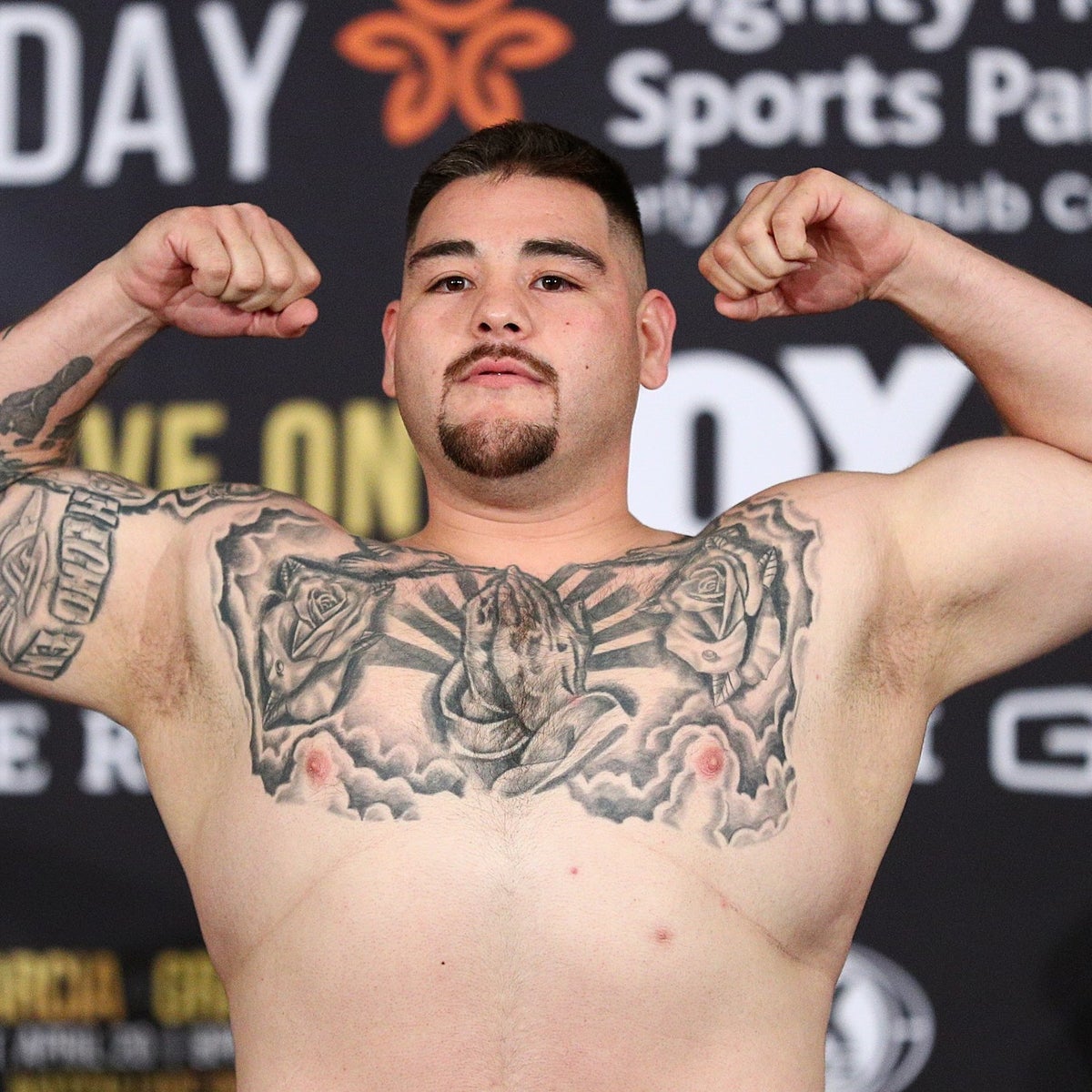 Andy Ruiz Jr. tattoos: close weigh-in portrait showing the central chest piece, roses, praying hands, and arm work