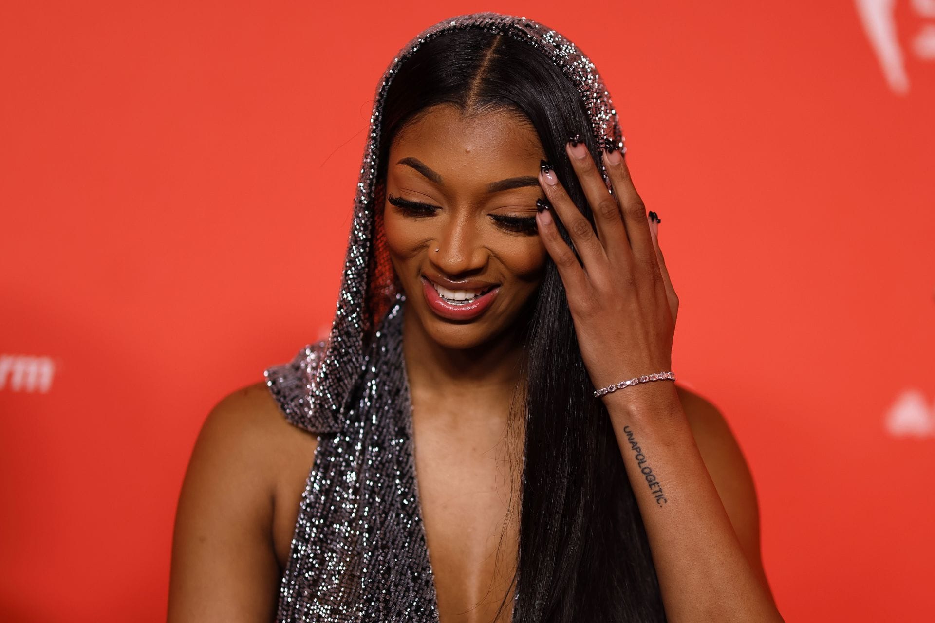 Angel Reese tattoos: Clear event photograph showing the documented UNAPOLOGETIC lettering on her lower forearm