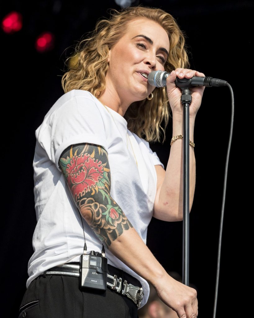 Anouk tattoos: live performance photograph with Anouk's colorful floral sleeve fully exposed from the upper arm down toward the elbow