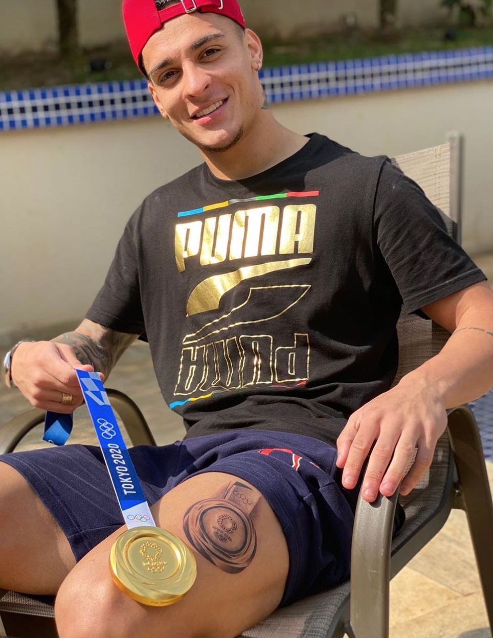 Antony tattoos: clear seated portrait showing the Olympic medal tattoo on the thigh