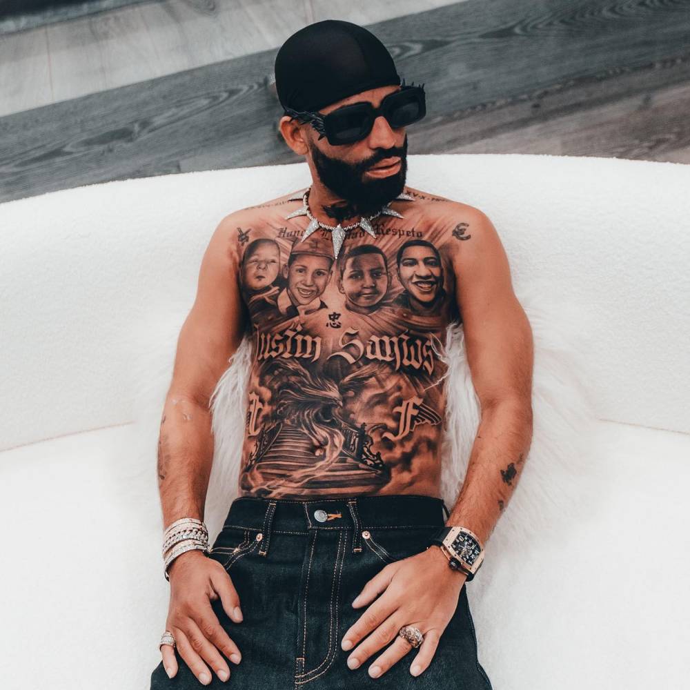 Arcángel tattoos: Tattoo evidence: full-torso seated view showing the four memorial portraits, lettering and lower composition.