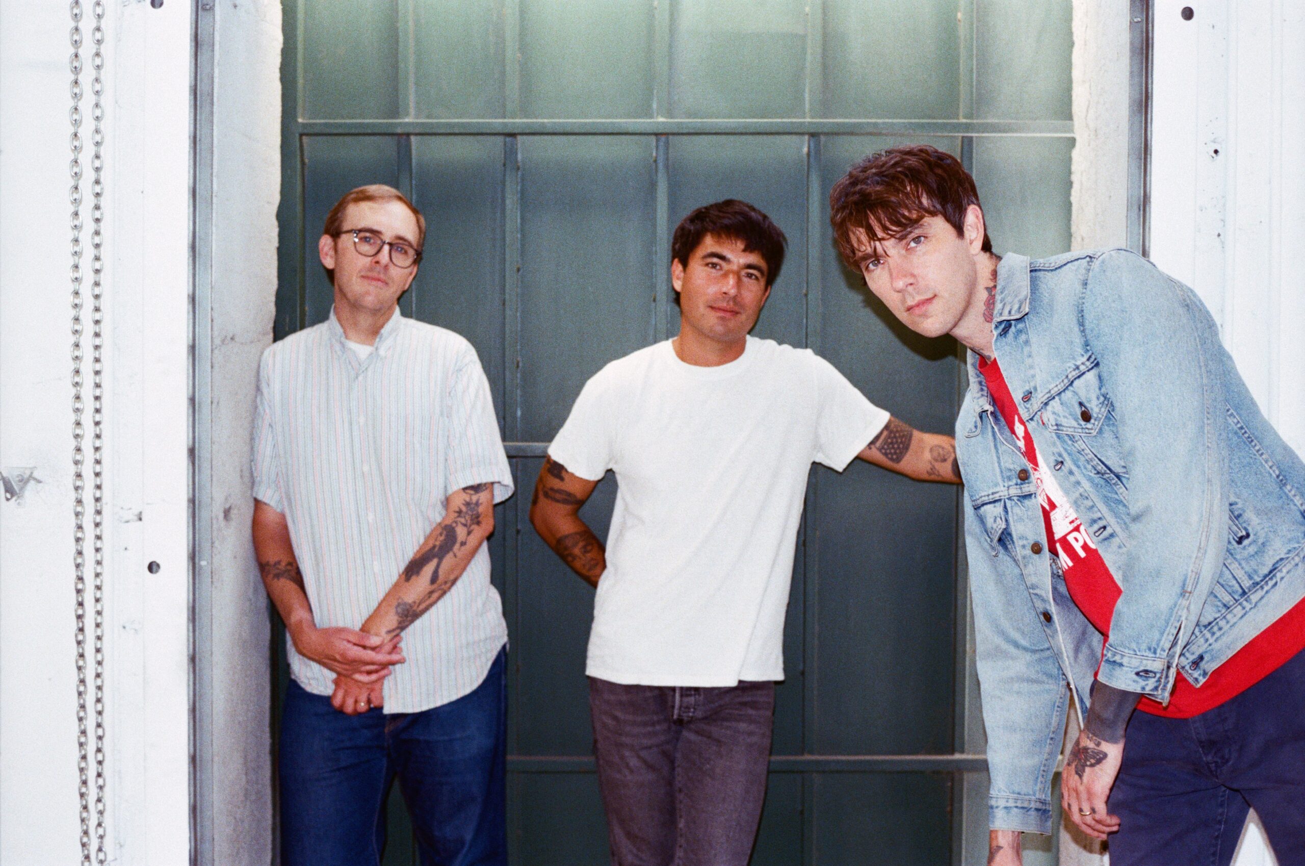 Barry Johnson tattoos: Genuine tattoo photograph showing Barry Johnson at right with visible neck and arm ink in an official band portrait.