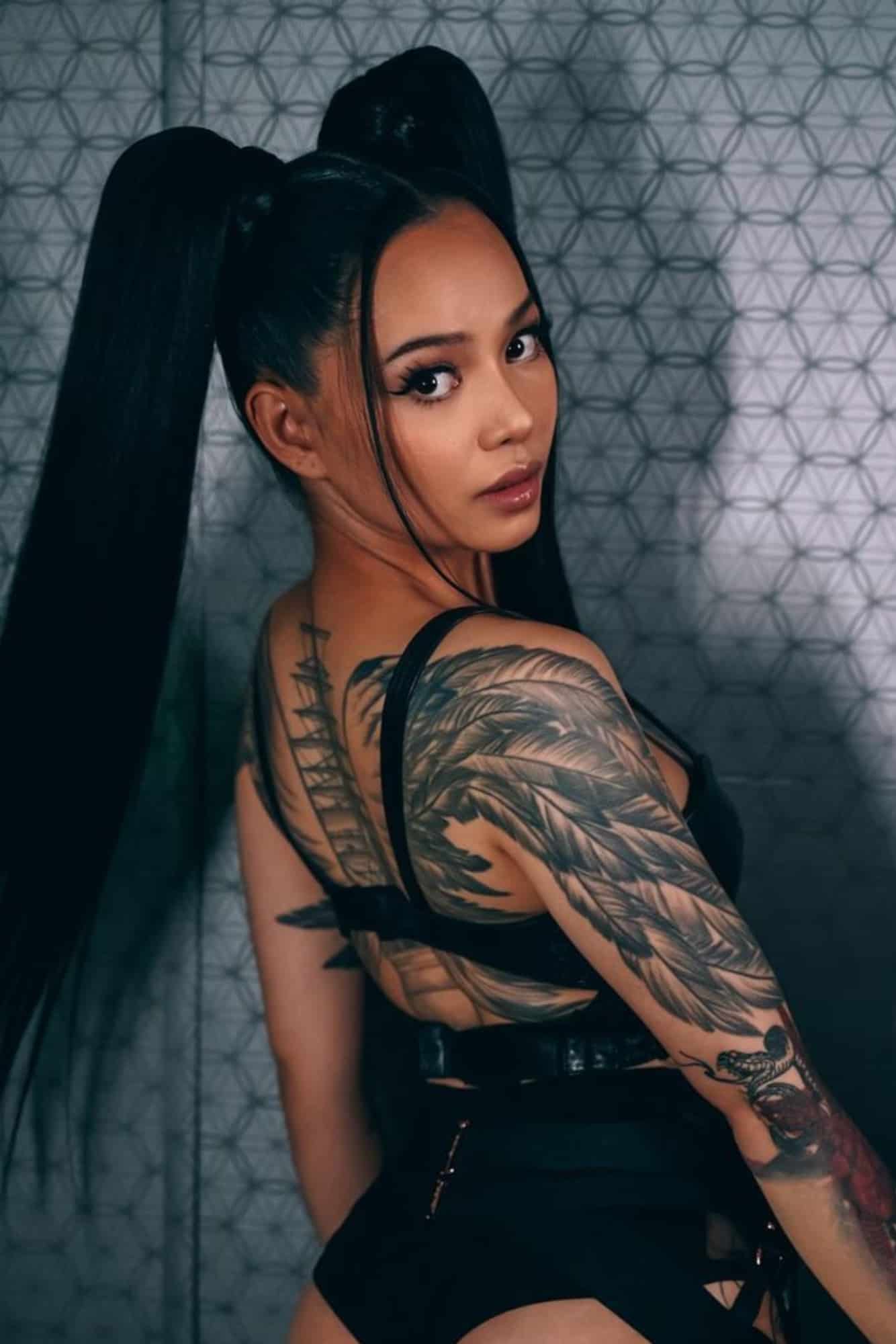 Bella Poarch tattoos: arm feathers and chest lettering