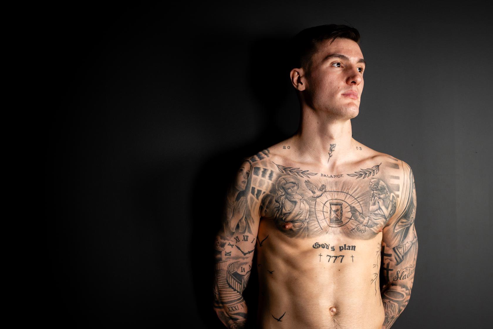 Benjamin Šeško Wide official portrait showing BALANCE, God’s Plan, chest illustrations and both tattooed arms Benjamin Šeško tattoos: Wide official portrait showing BALANCE, God’s Plan, chest illustrations and both tattooed arms
