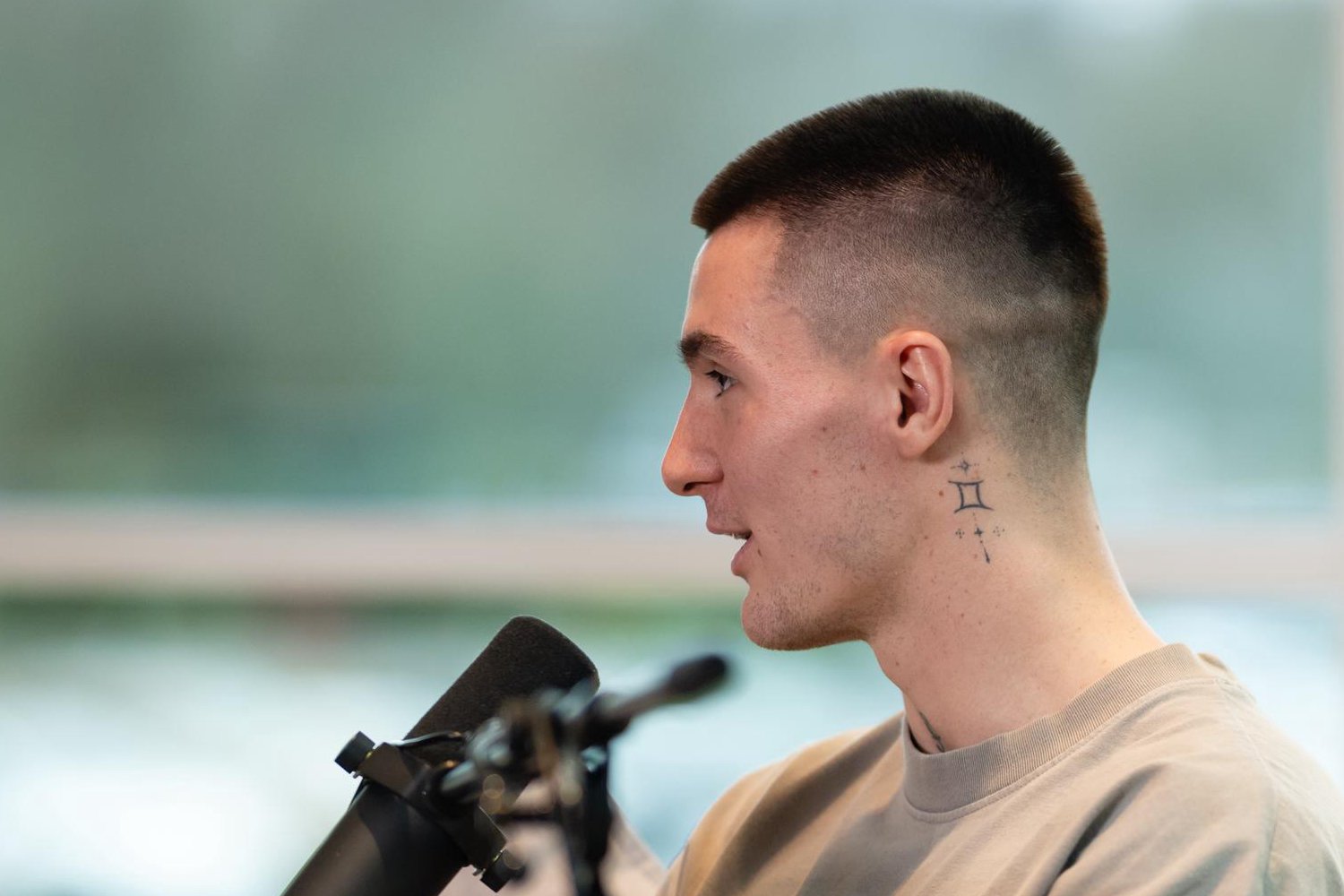 Benjamin Šeško Close side-profile interview photograph isolating the small tattoo below the ear and neck rose area Benjamin Šeško tattoos: Close side-profile interview photograph isolating the small tattoo below the ear and neck rose area