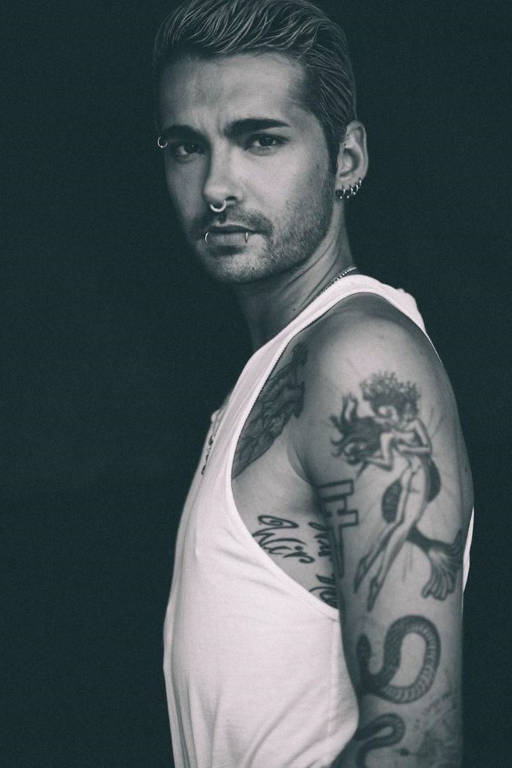 Bill Kaulitz tattoos: high-resolution tank-top portrait showing the snake, figure, script and layered arm tattoos without generic filler imagery