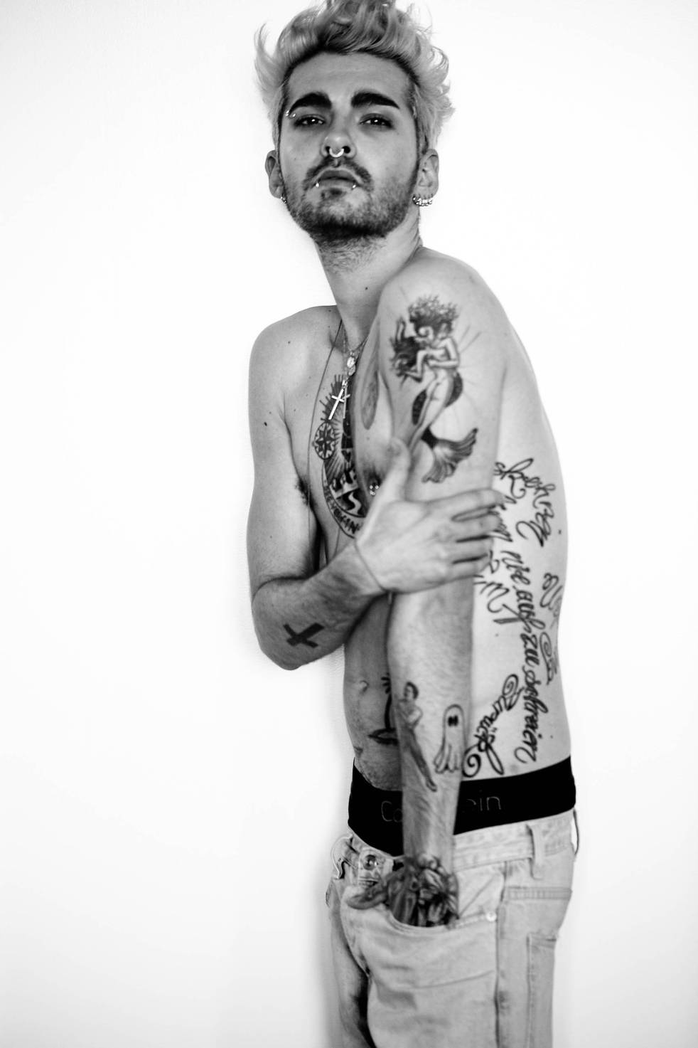 Bill Kaulitz tattoos: side portrait showing the large mermaid on the upper arm, long script along the ribs and smaller lower-arm designs