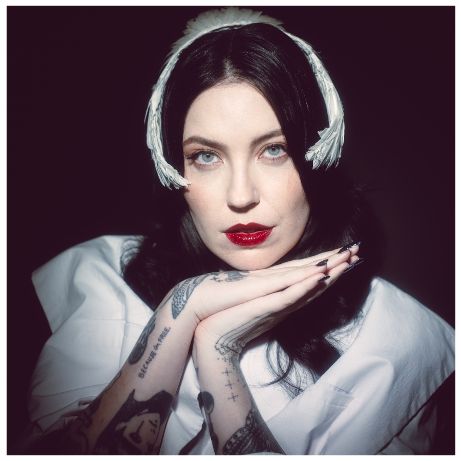 Bishop Briggs tattoos: Close portrait showing tattooed hands and wrists, lettering and small illustrative shapes.