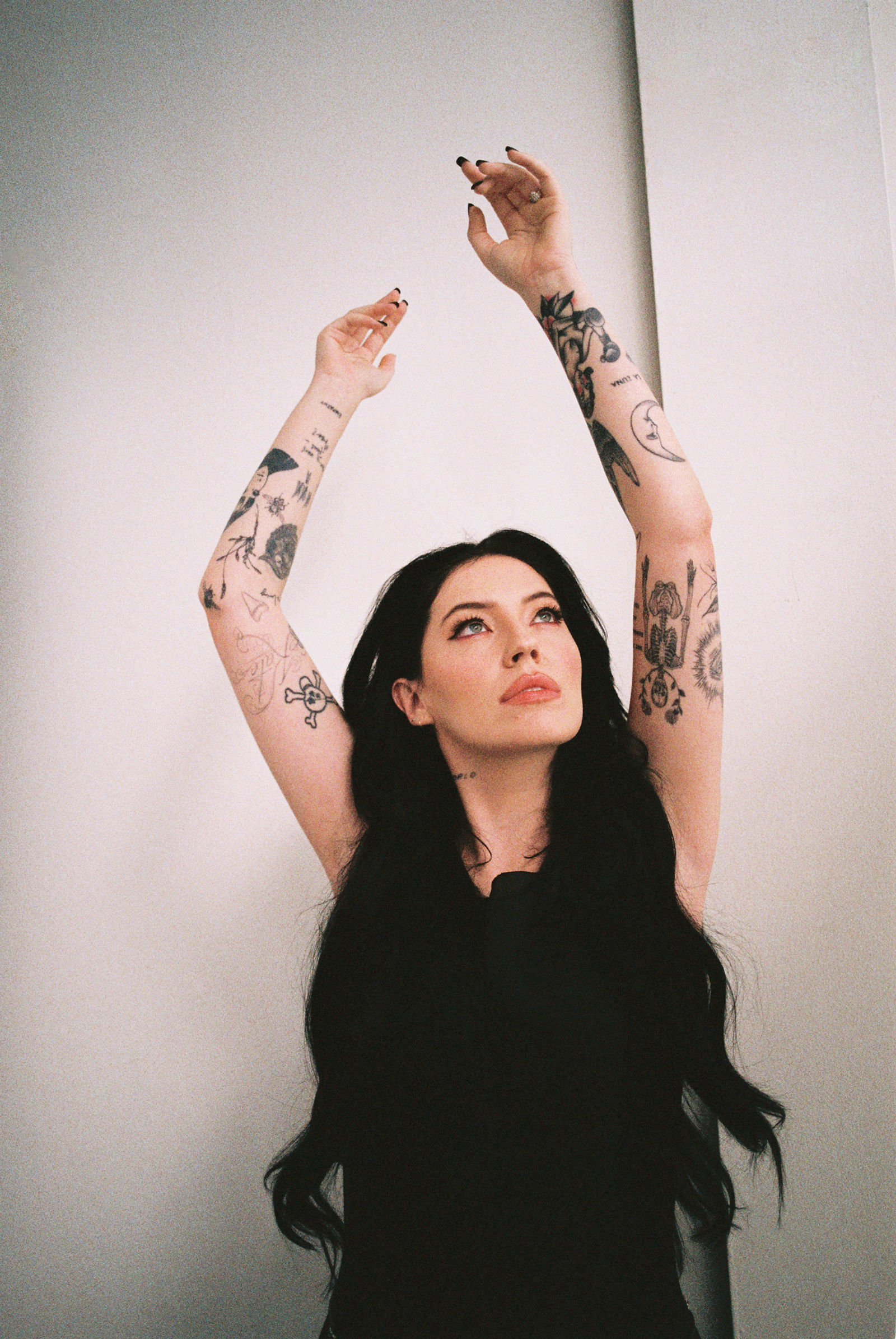 Bishop Briggs tattoos: Full portrait showing both tattooed arms, wrist lettering and smaller symbolic pieces.