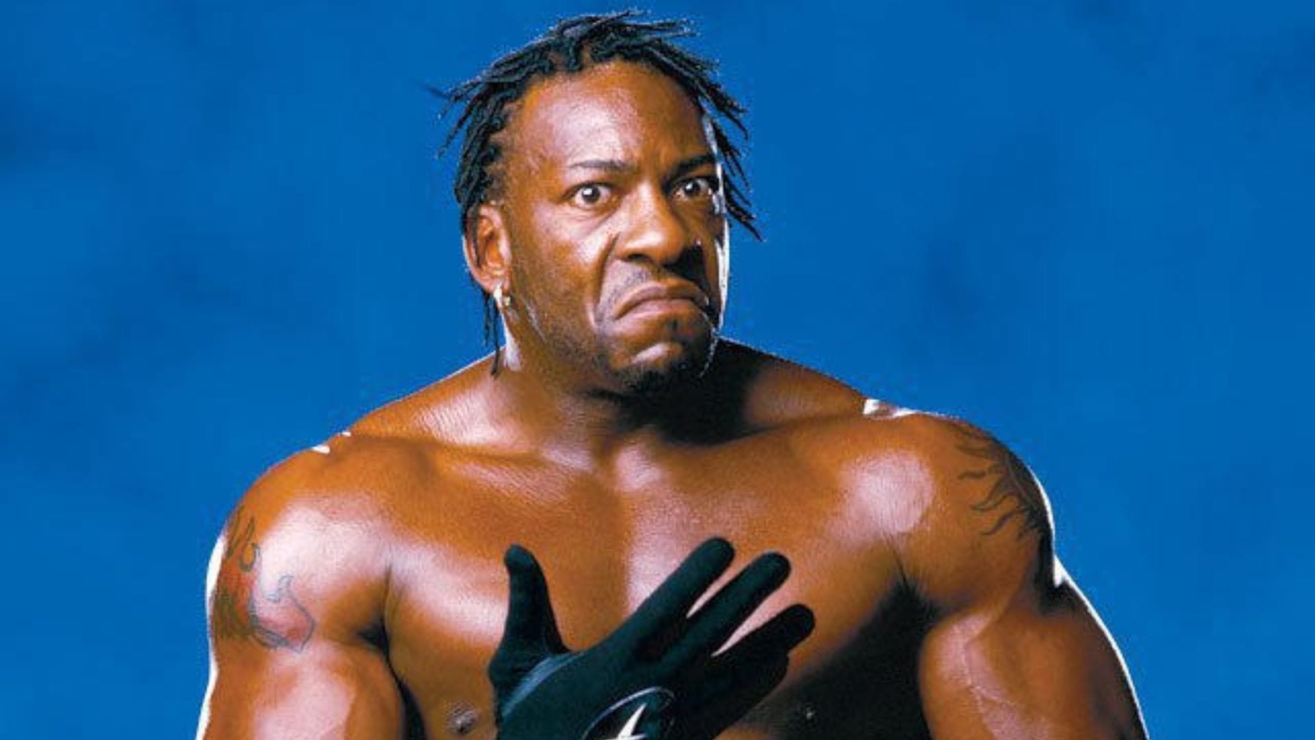 Booker T blue-background portrait showing both shoulder tattoos