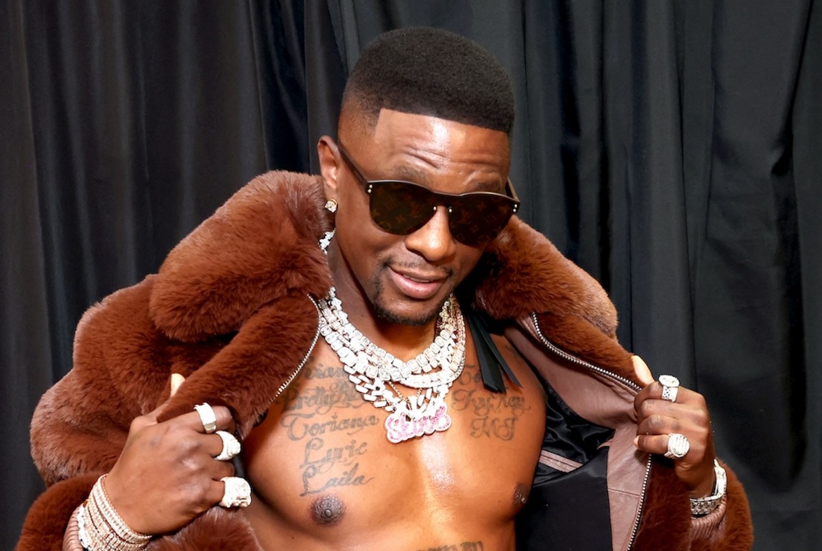Boosie BadAzz tattoos: shirtless fur-coat portrait showing the large family-name tattoos across his chest