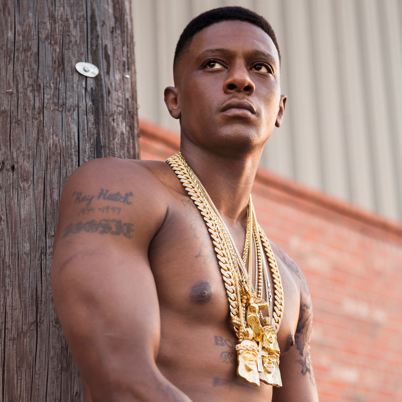 Boosie BadAzz tattoos: portrait showing the Torrence Hatch name and date tattoo on the upper arm