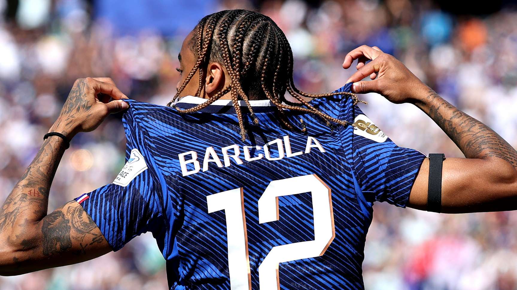 Bradley Barcola tattoos: Goal football photograph showing Bradley Barcola’s face turned away, hands and tattooed forearms visible around the jersey