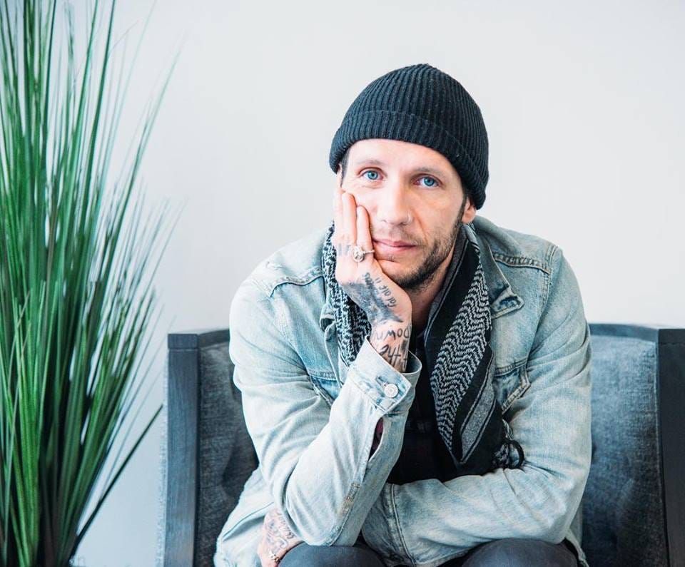 Brandon Novak tattoos: face-visible portrait with tattooed hand and forearm resting against the face