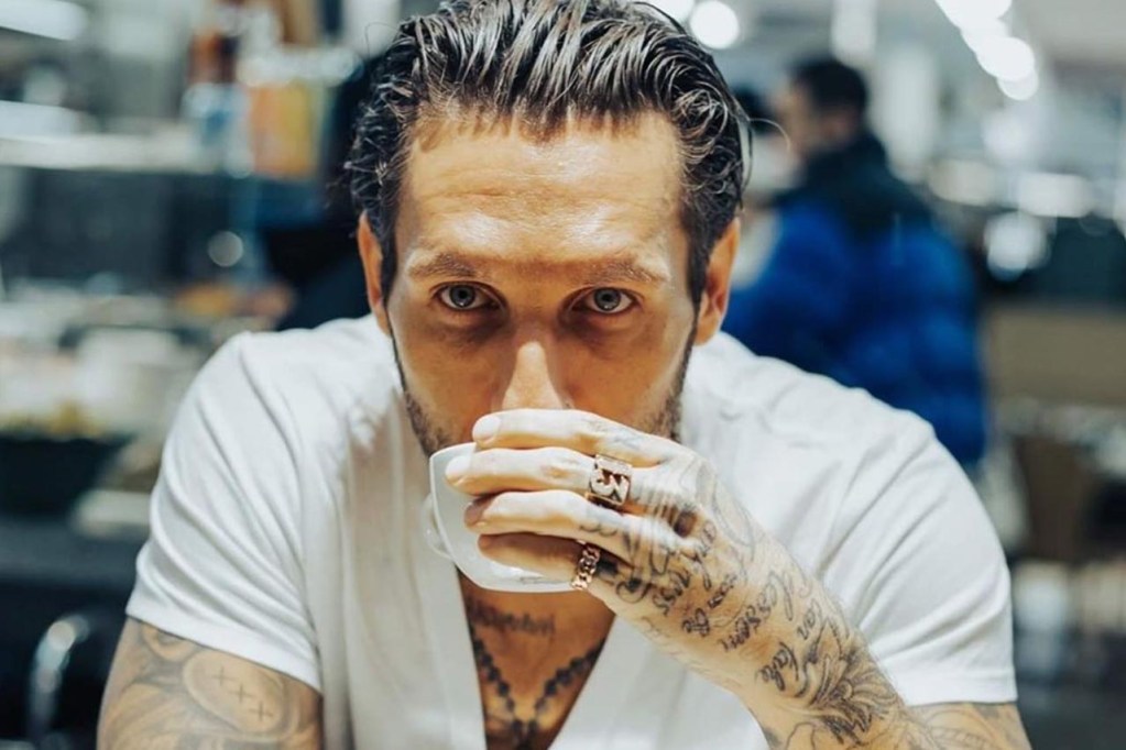 Brandon Novak tattoos: close portrait showing hand lettering, finger marks and visible chest symbols
