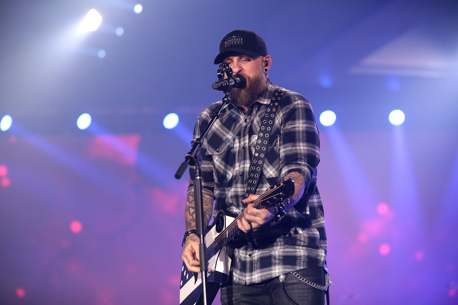 Brantley Gilbert sleeve tattoos while singing into a microphone