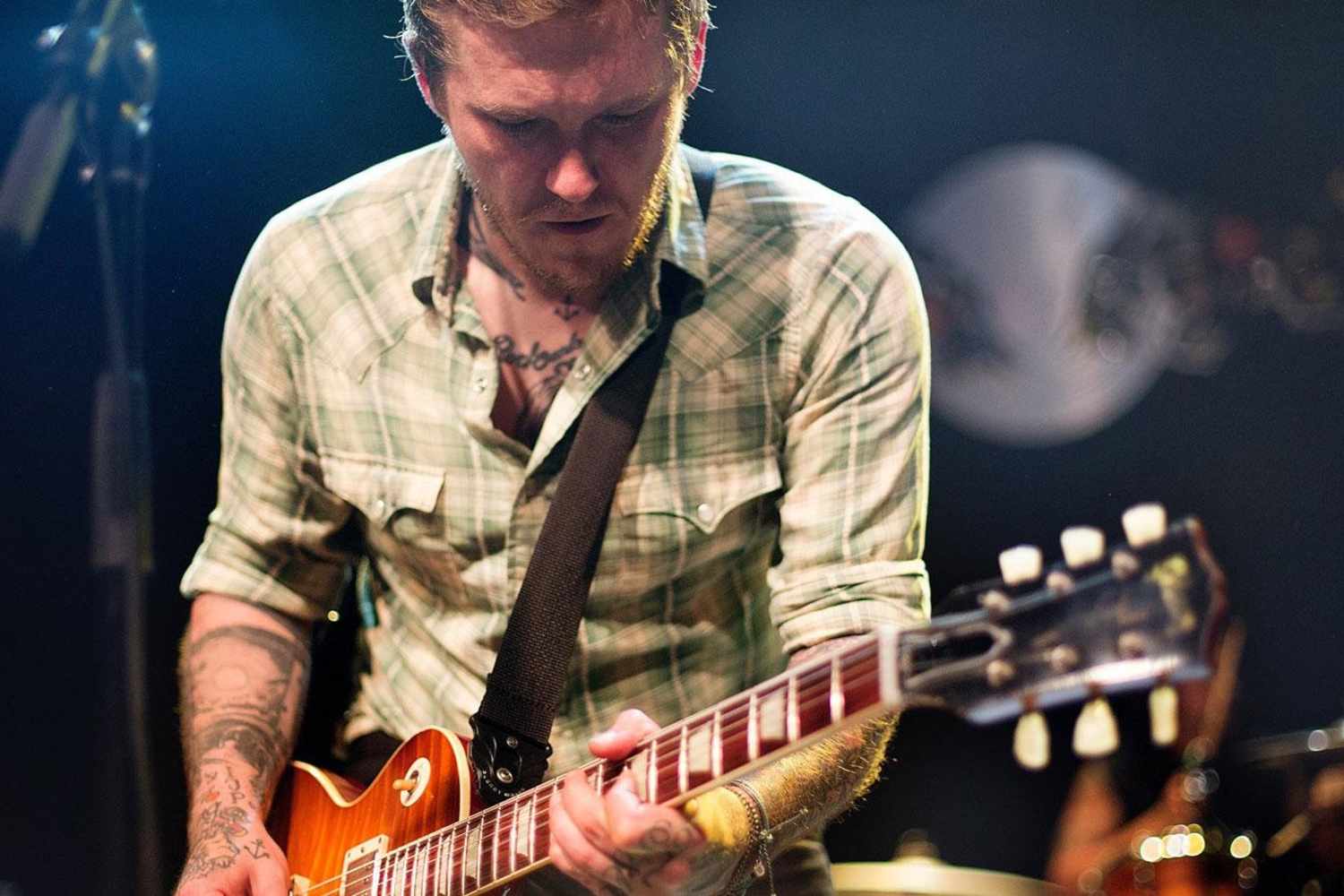 Brian Fallon tattoos: visible neck, chest and forearm tattoos while playing guitar