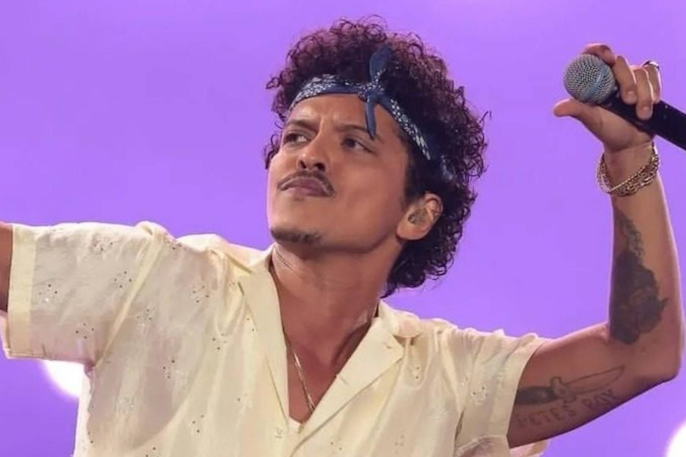Bruno Mars tattoos: performance photograph showing the knife and Pete’s Boy lettering on Bruno Mars’s raised arm