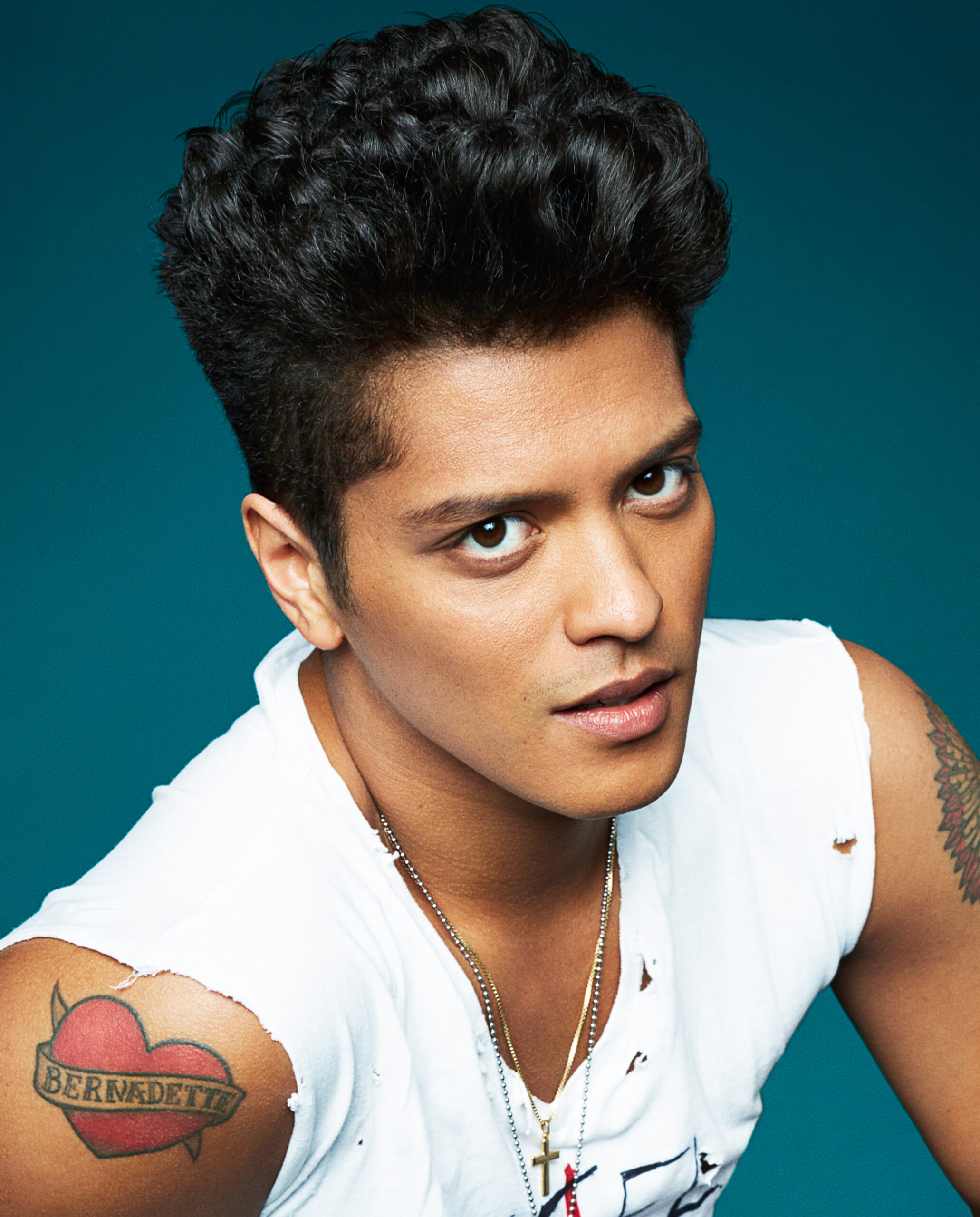 Bruno Mars tattoos: portrait close-up clearly showing the red Bernadette heart and banner on Bruno Mars’s upper arm