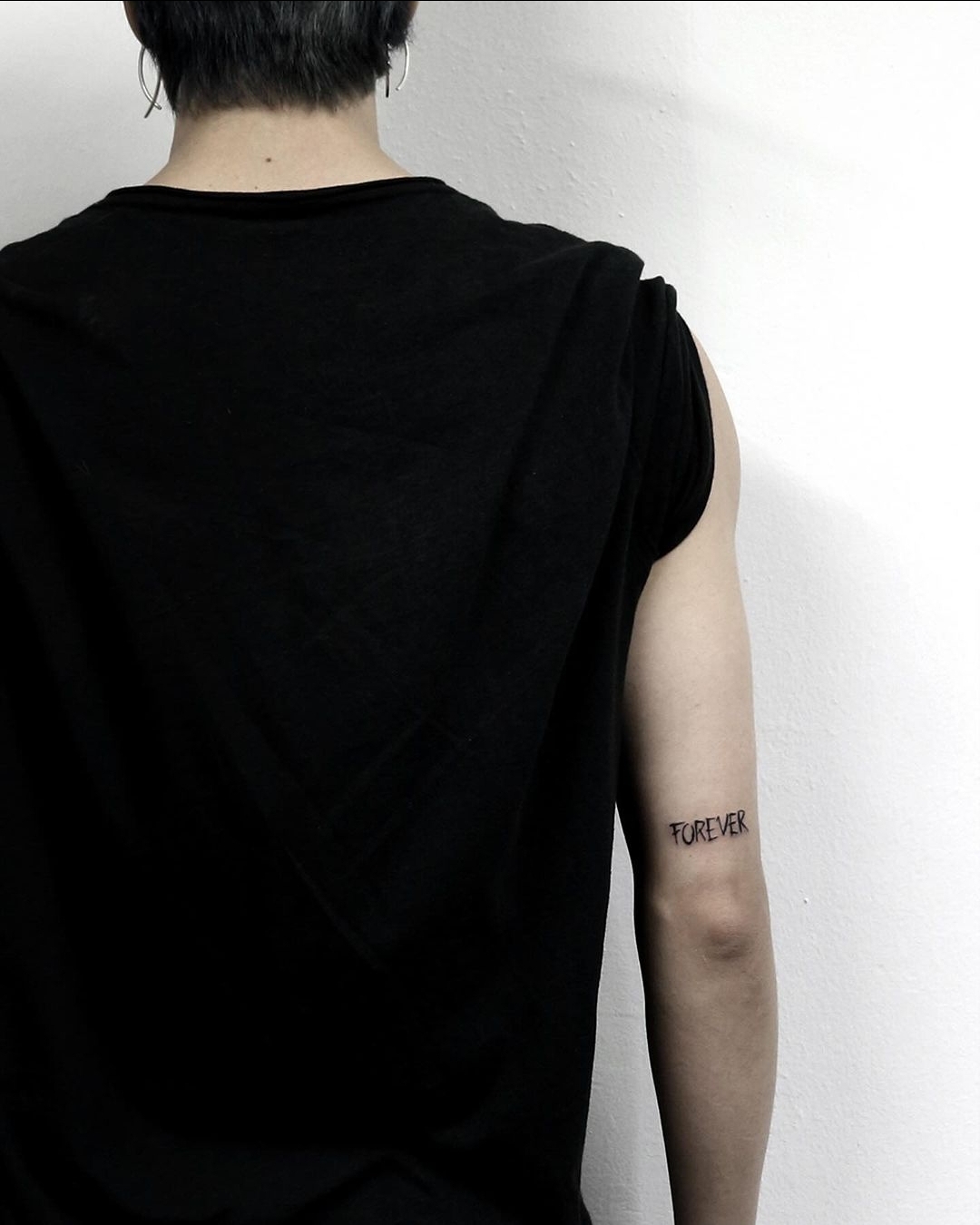 BTS Jimin tattoos: Rear arm photograph documenting the FOREVER lettering.
