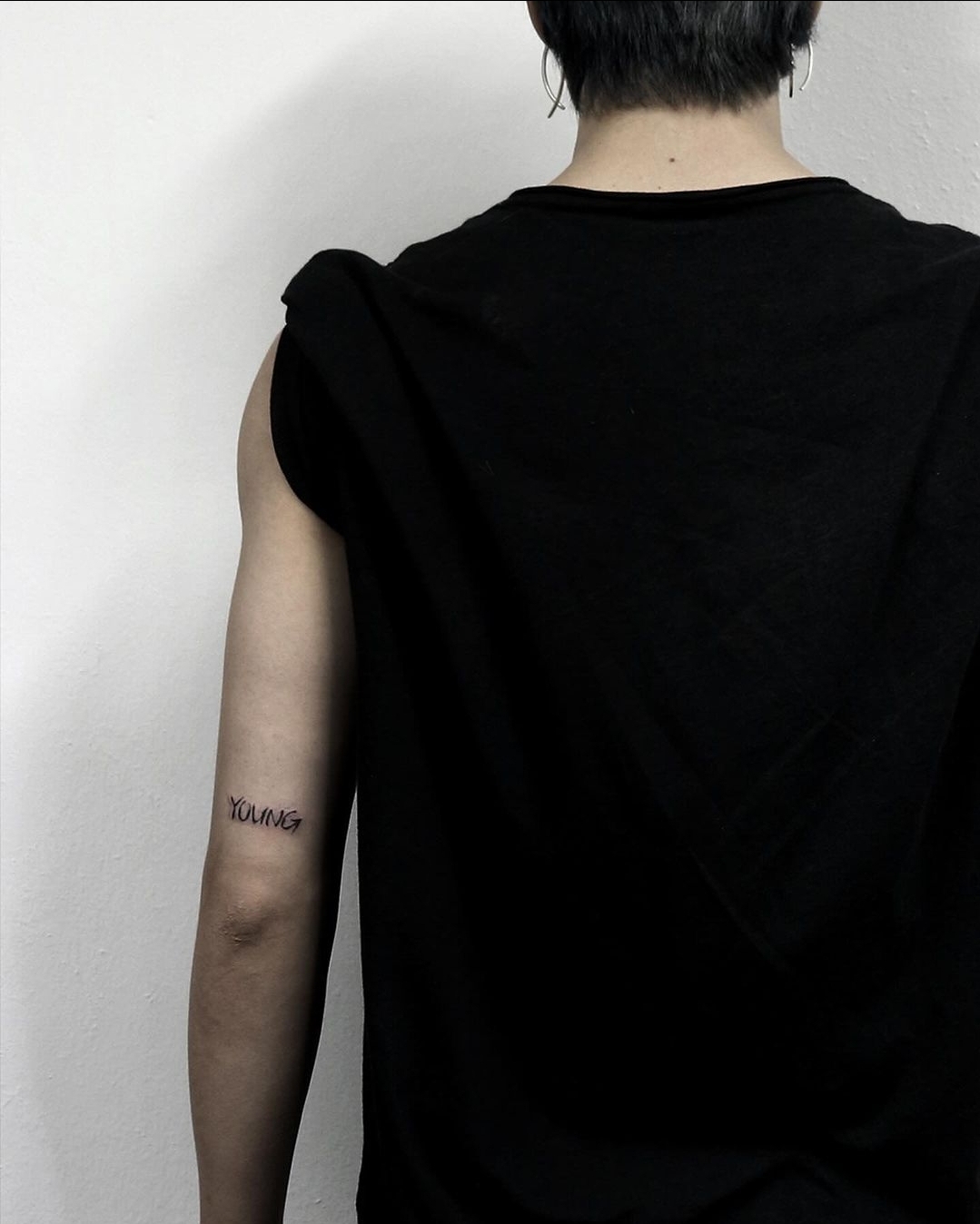 BTS Jimin tattoos: Rear arm photograph documenting the YOUNG lettering.