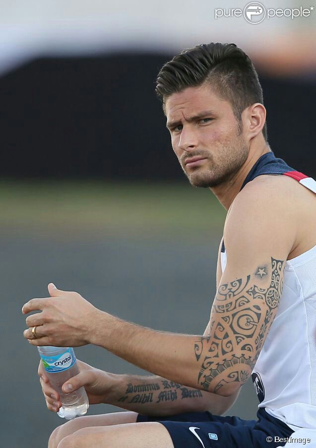 Olivier Giroud tattoos: Olivier Giroud seated close-up showing Latin forearm lettering and tribal sleeve