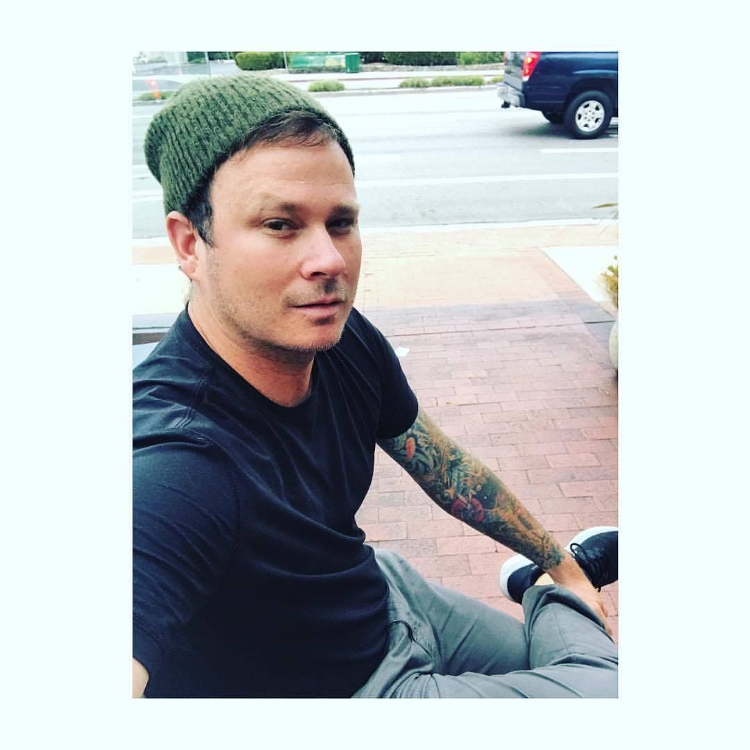 Tom DeLonge tattoos: casual outdoor portrait with the tattooed arm resting in the foreground, showing how the sleeve looks away from a stage
