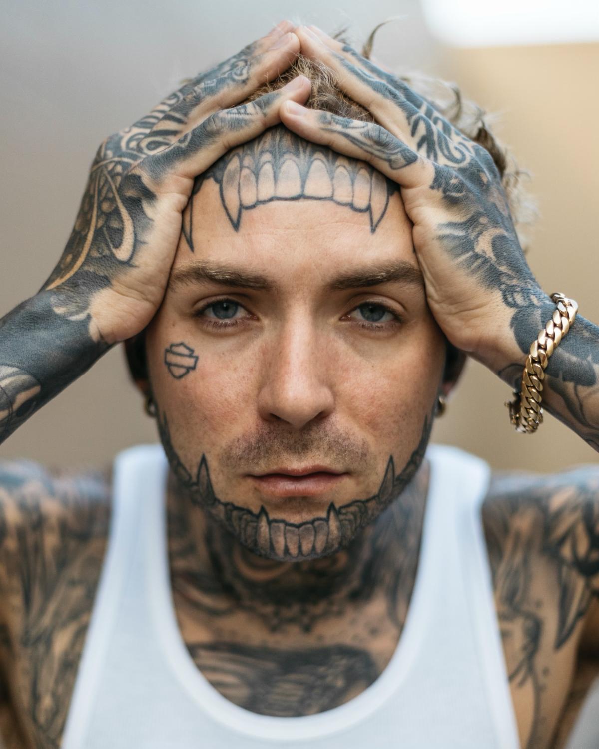 Caskey tattoos: high-resolution portrait showing the face, neck, chest, hands and arms covered in tattoos