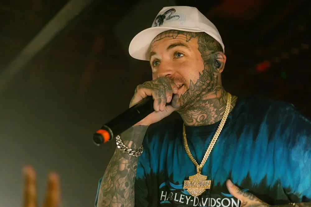 Caskey tattoos: high-resolution live performance photo showing face, neck, hands and arm tattoos