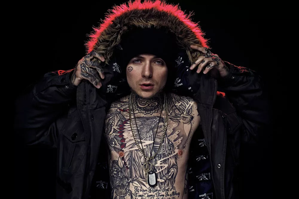 Caskey tattoos: high-resolution hooded portrait showing the tattooed chest, neck and arms