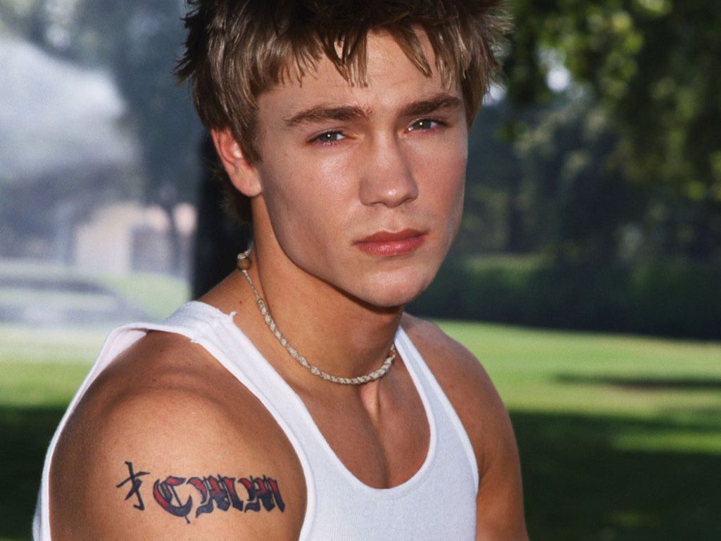 Chad Michael Murray tattoos: Genuine shoulder tattoo photograph with lettering and colored central detail.
