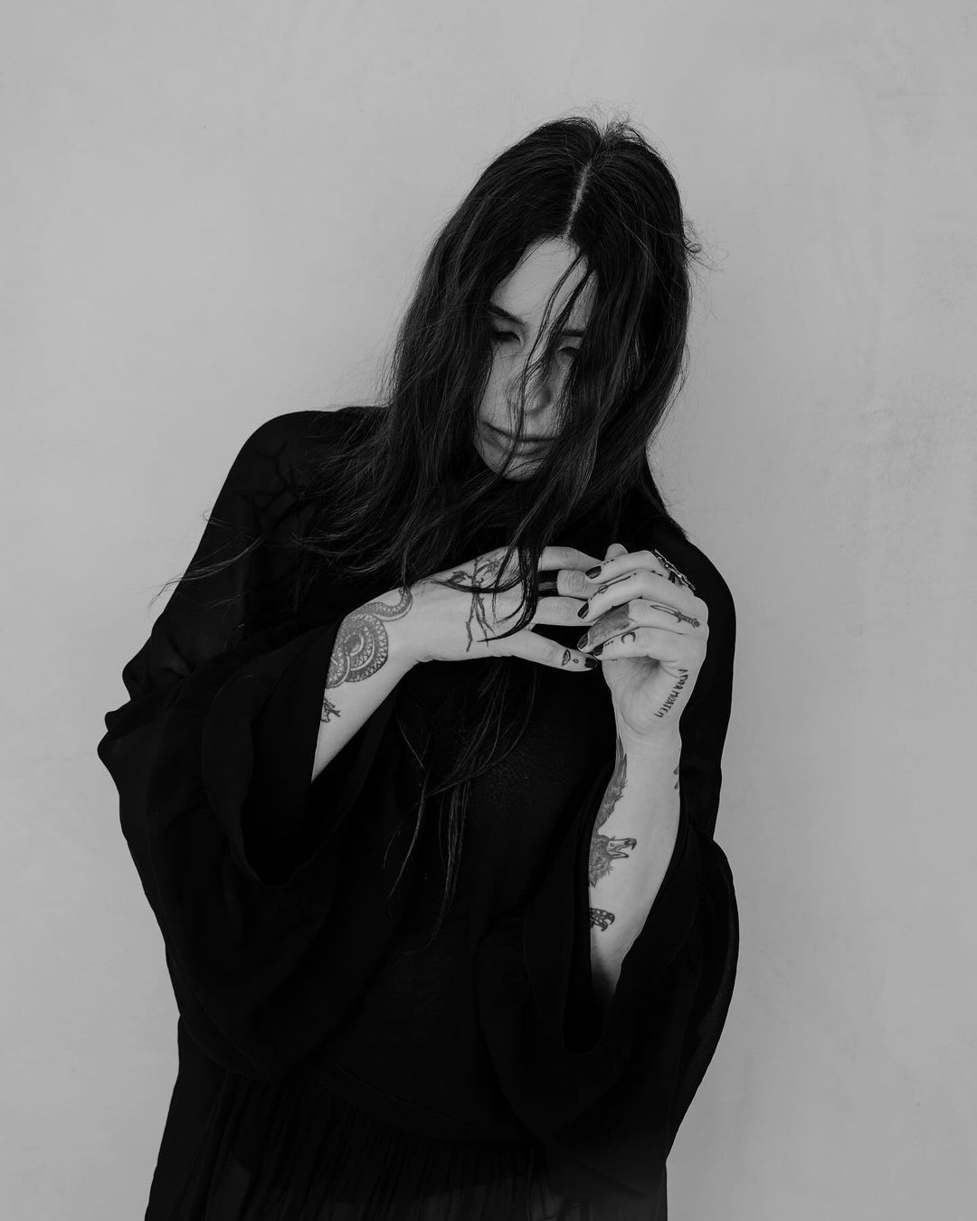 Chelsea Wolfe tattoos: crossed arms with geometric marks, dots, and fan-like shapes