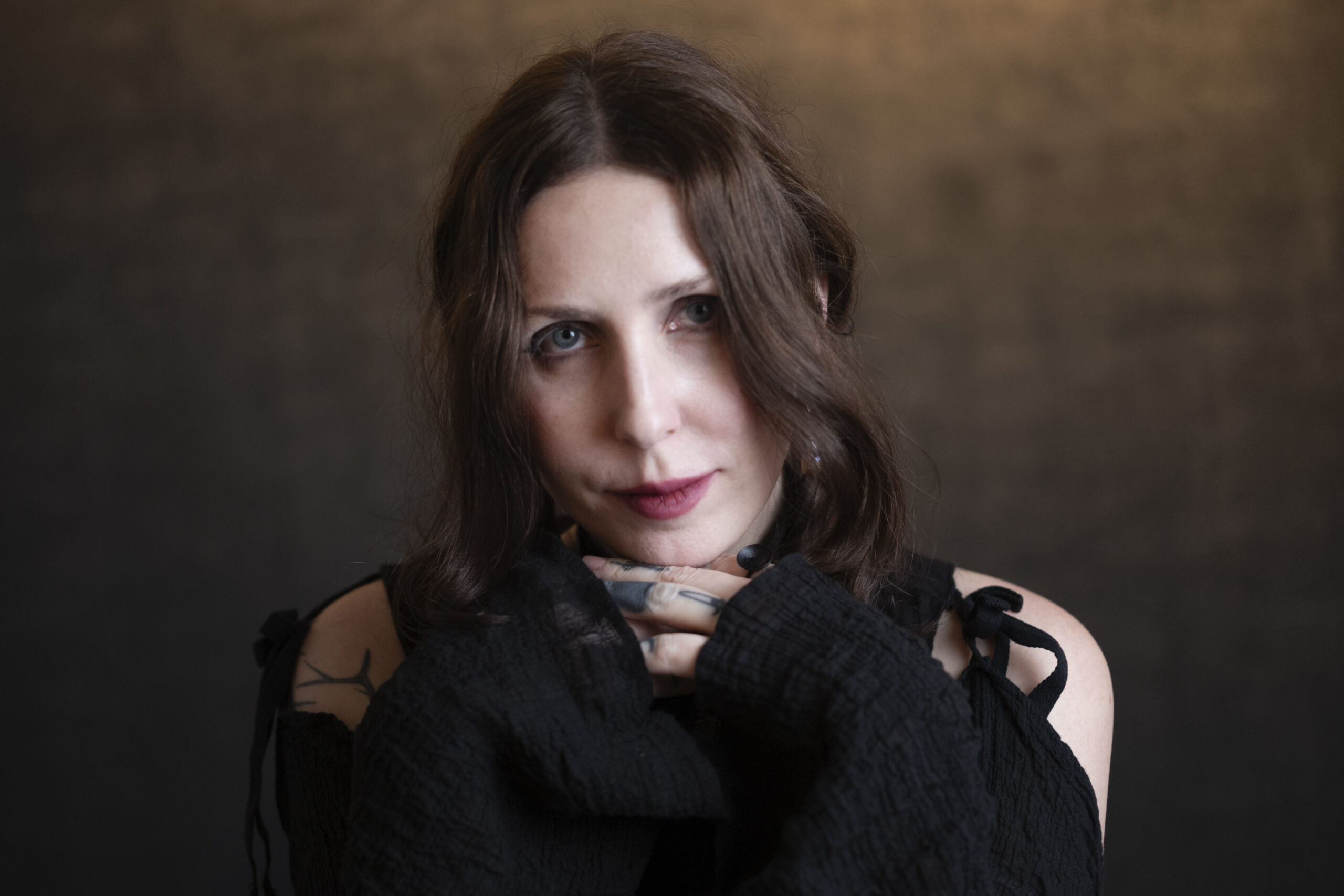 Chelsea Wolfe tattoos: a face-visible portrait with small hand, finger, and shoulder tattoos