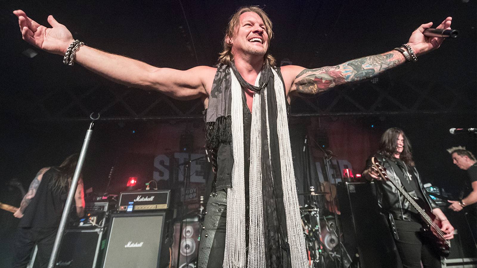 Chris Jericho showing both tattooed arms onstage
