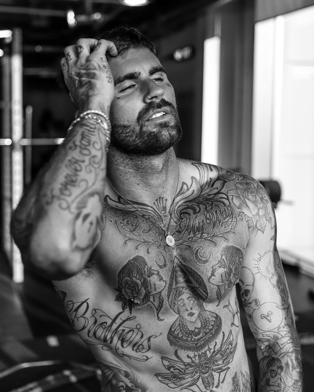 Chris Perceval tattoos: Ornamental upper-chest lettering with curling flourishes above paired profile portraits
