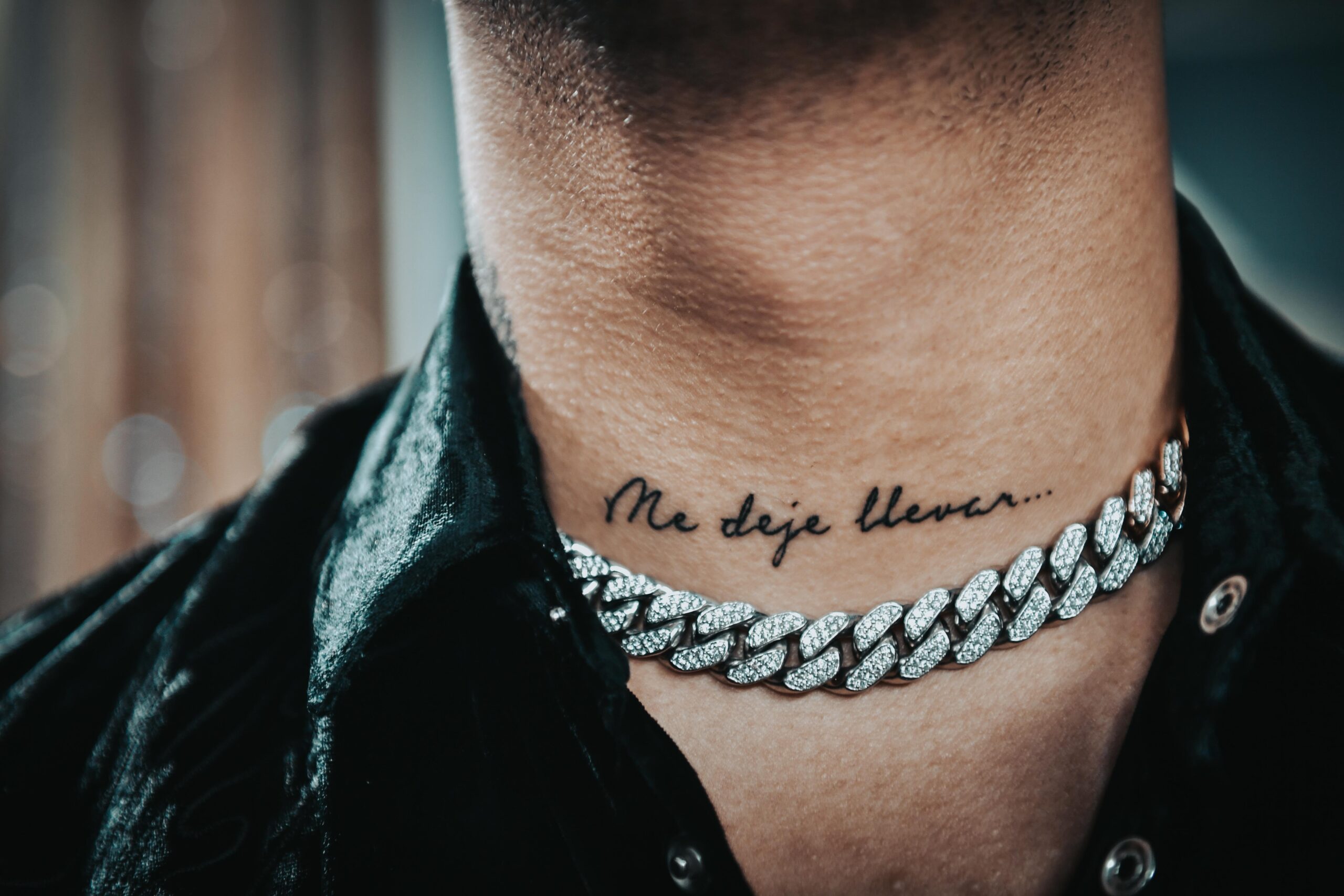 Christian Nodal tattoos: neck script tattoo reading Me deje llevar