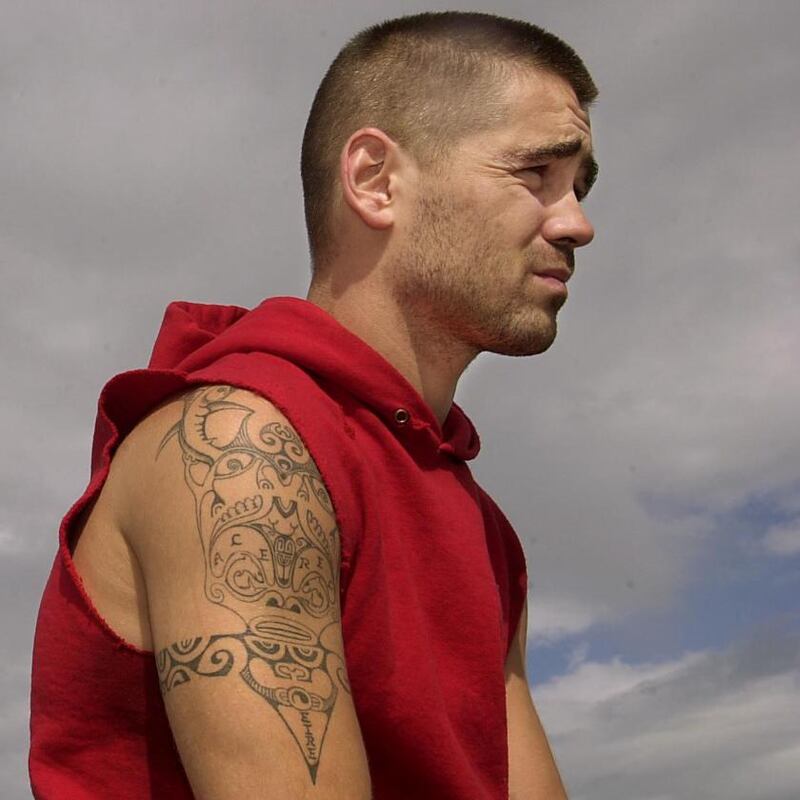 Colin Farrell wearing a red hoodie with his detailed arm tattoo visible