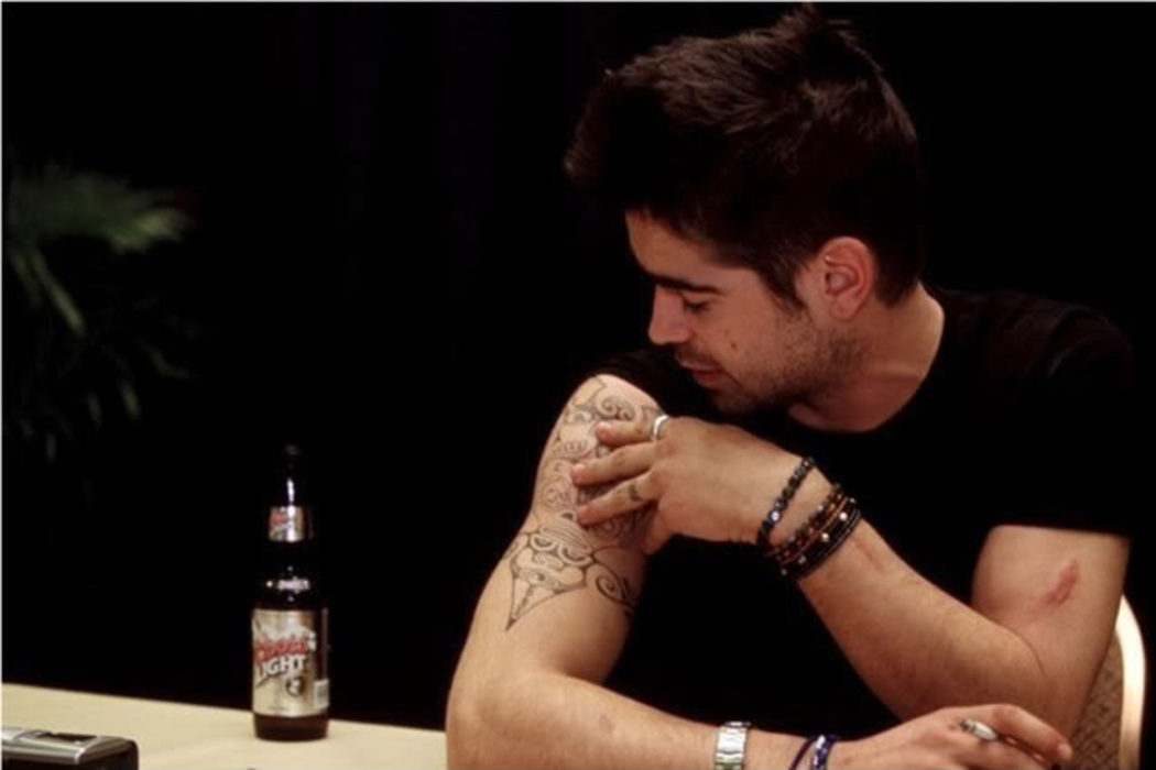 Colin Farrell looking closely at the tattoo on his upper arm