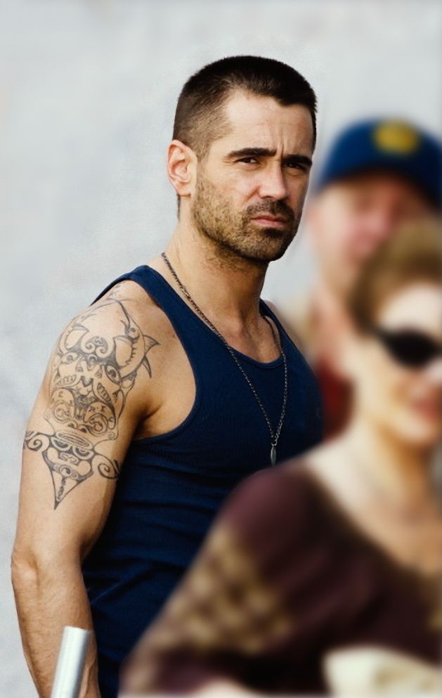Colin Farrell in a navy tank top with his upper arm tattoo visible