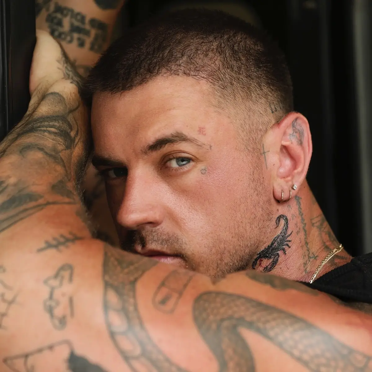Cooper Black tattoos: Face and neck close-up showing the small facial heart and surrounding ink