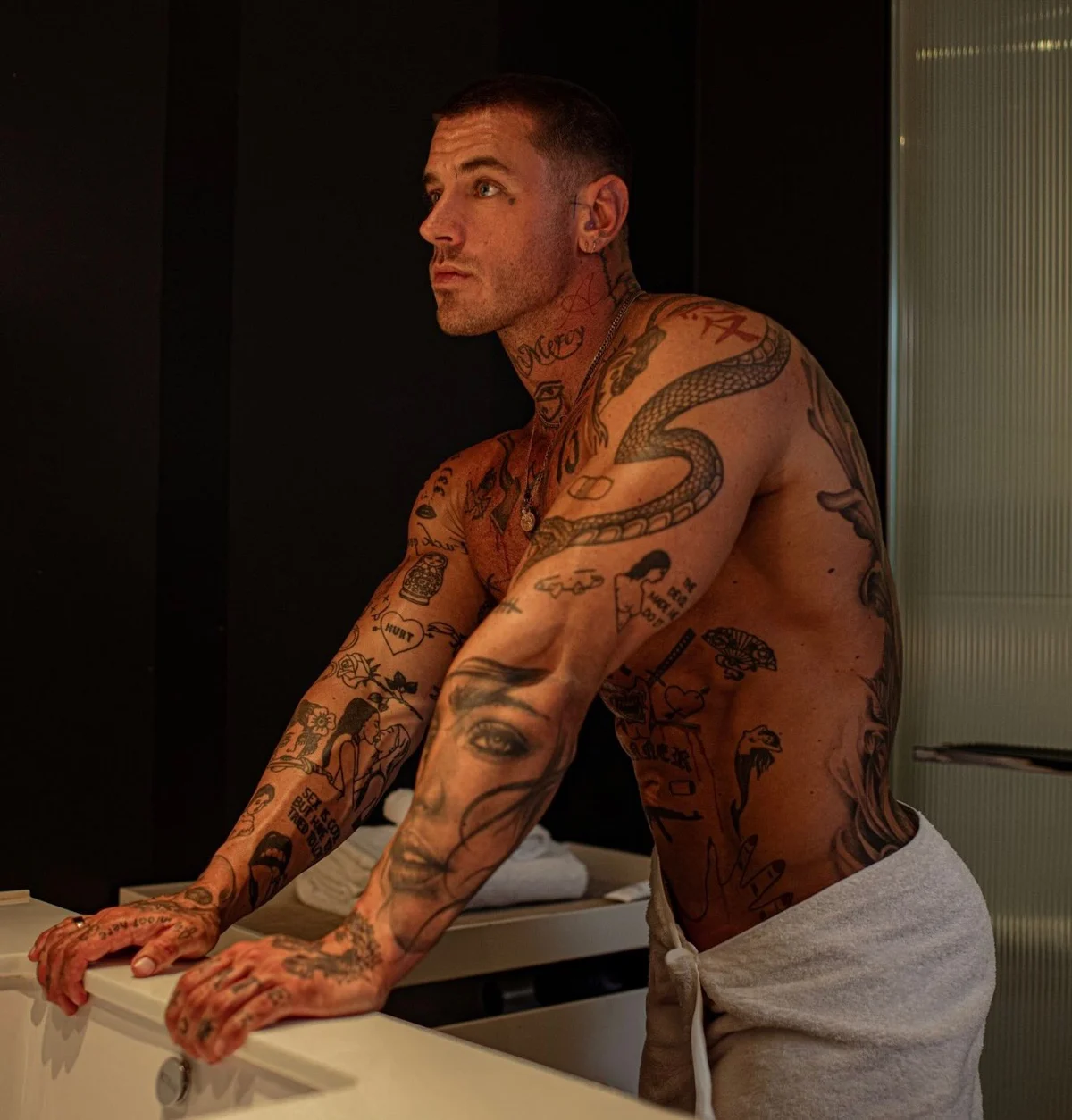 Cooper Black tattoos: Full upper-body photograph showing chest, arms, neck lettering and body symbols
