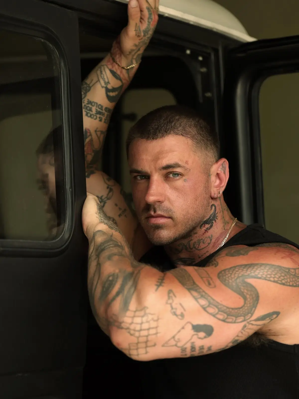 Cooper Black tattoos: Seated portrait showing the snake, arm lettering, chest and shoulder designs