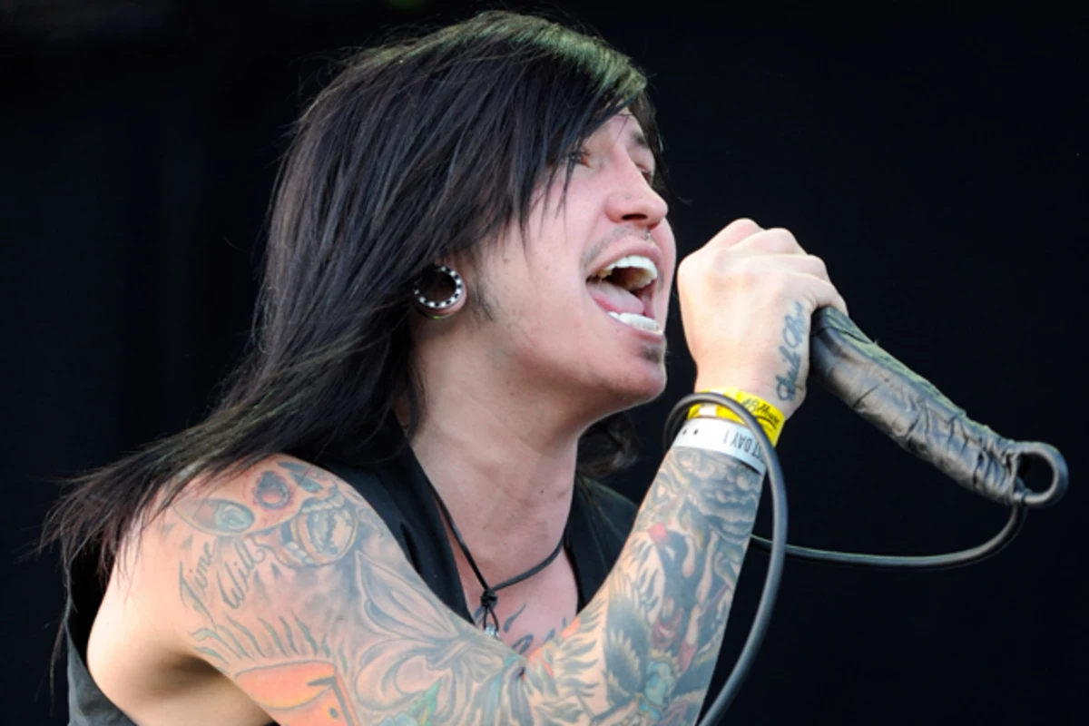 Craig Mabbitt tattoos: close performance photograph showing tattooed arms, neck and chest near the microphone