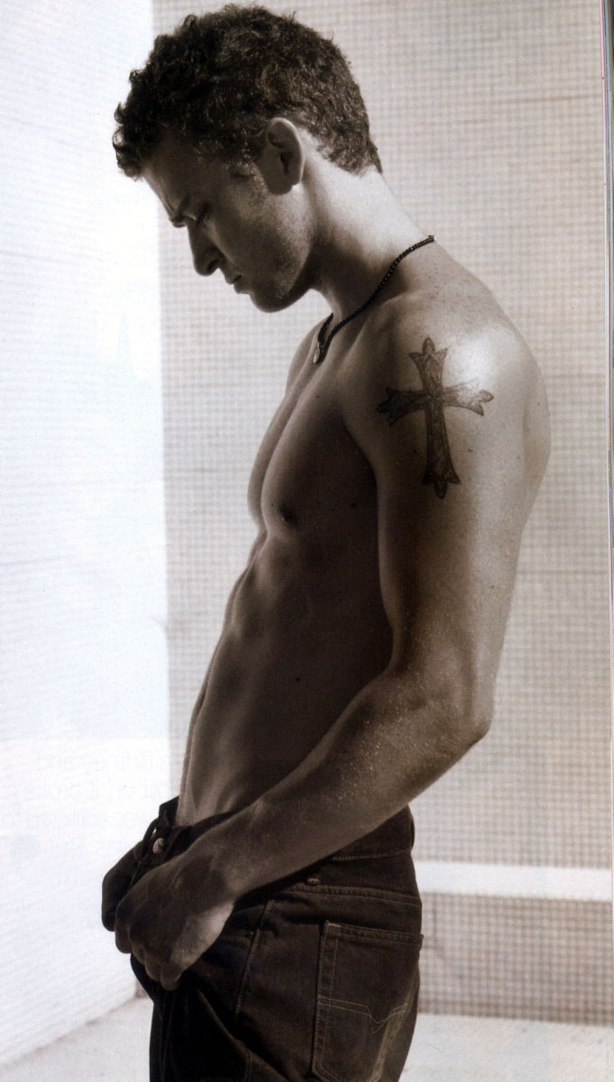 Justin Timberlake tattoos: upper-arm cross with clear traditional outline