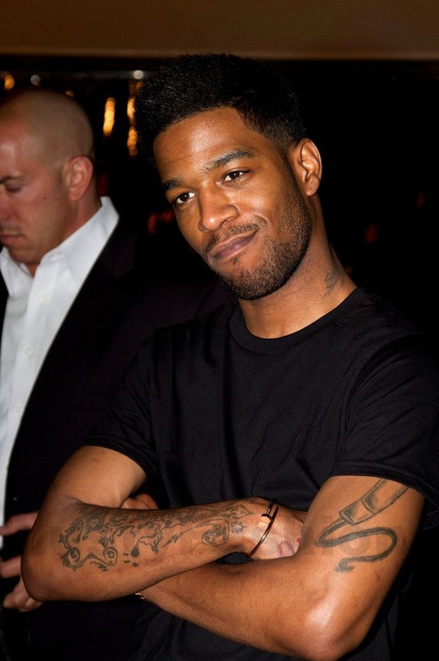 Kid Cudi forearm tattoos visible with arms crossed