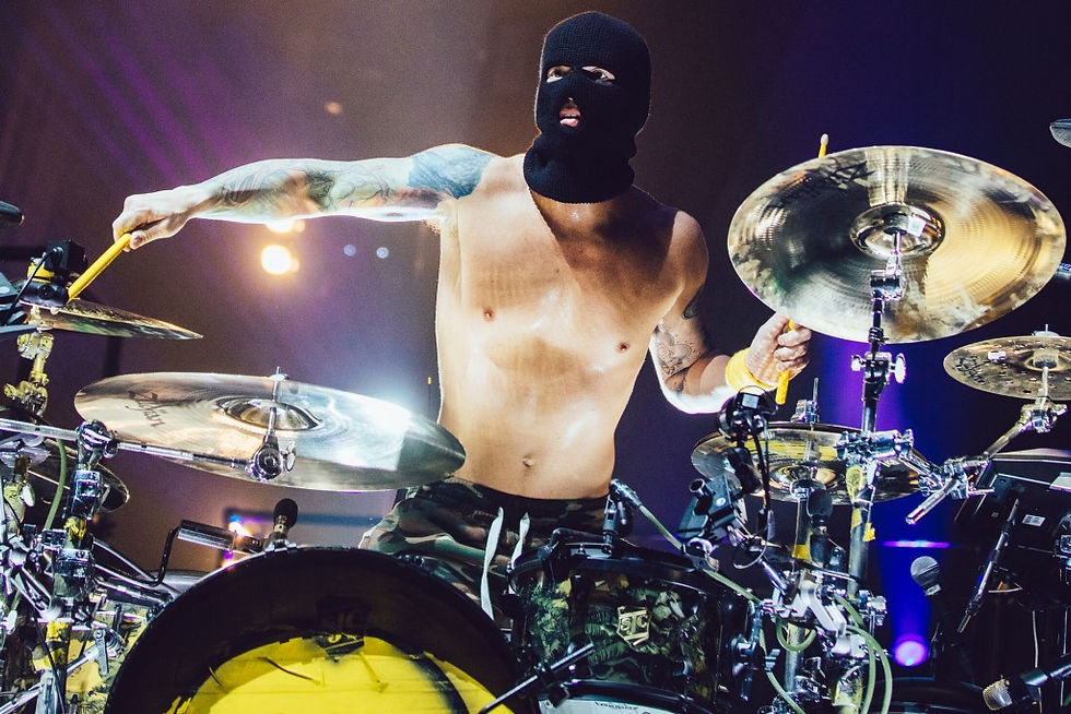 Josh Dun tattoos: stage image showing the contrasting colourful left arm and darker right-arm pieces