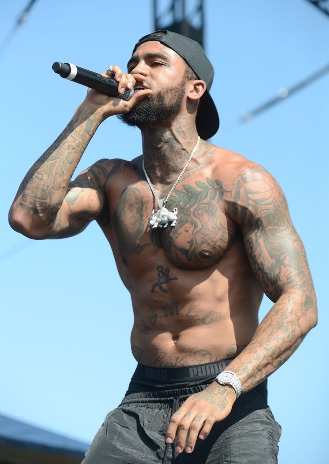 Dave East tattoos: high-resolution stage photograph showing the chest, shoulders, neck and forearm tattoos