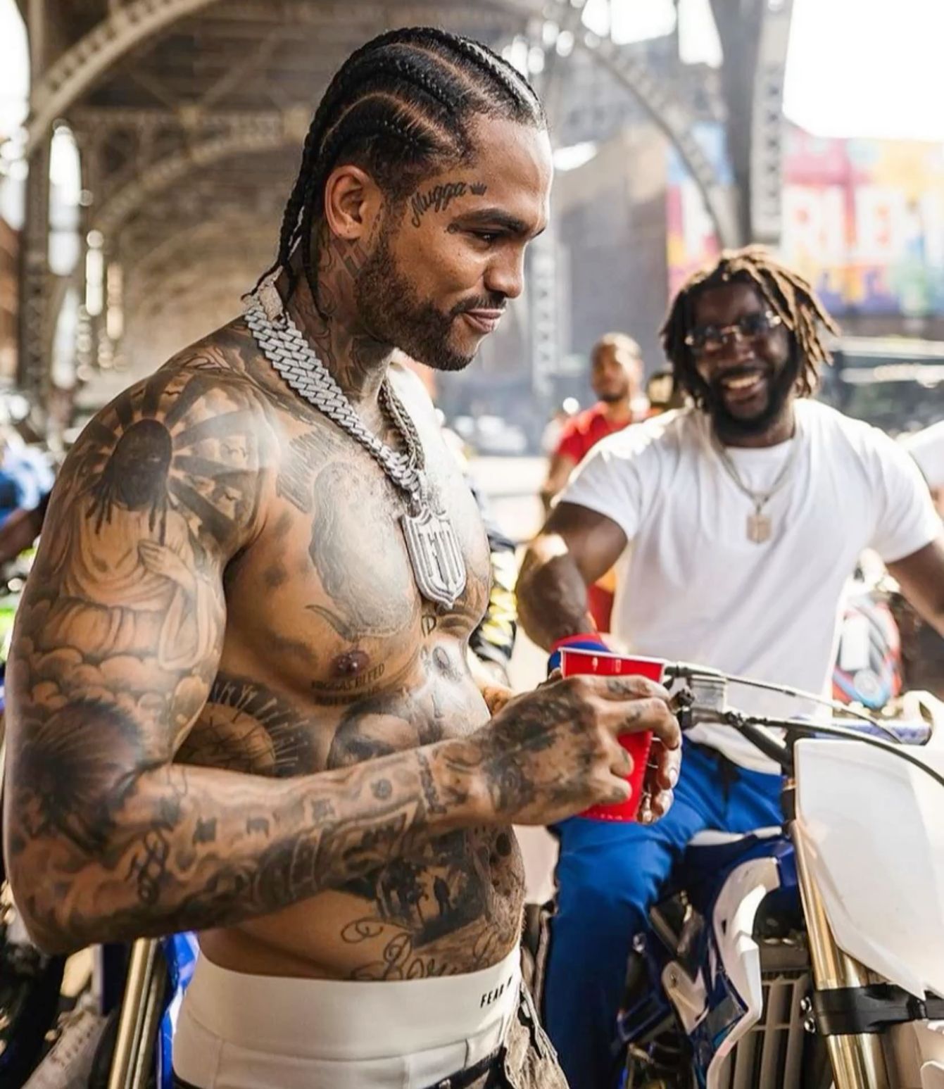 Dave East tattoos: high-resolution outdoor portrait showing the torso, arms and hand tattoos from the side
