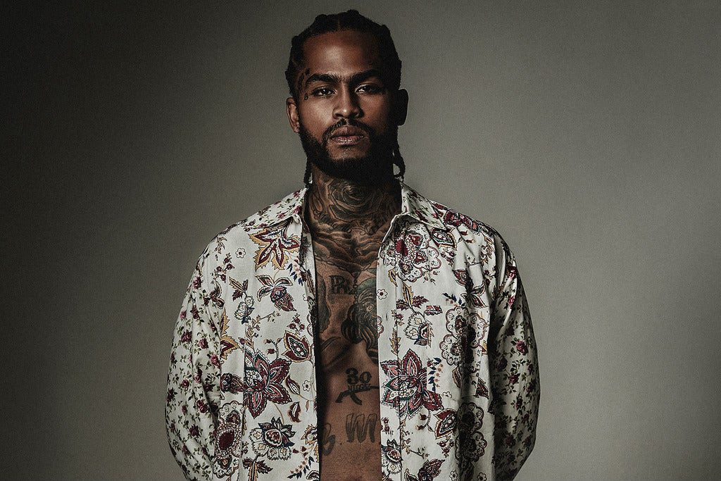 Dave East tattoos: high-resolution studio portrait showing the chest and neck tattoos through an open shirt