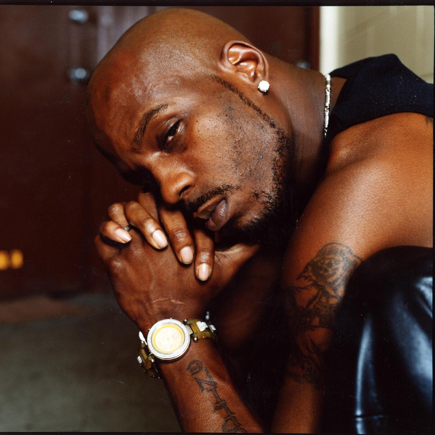 DMX tattoos: portrait view showing the large upper-arm piece, forearm script and hand placement